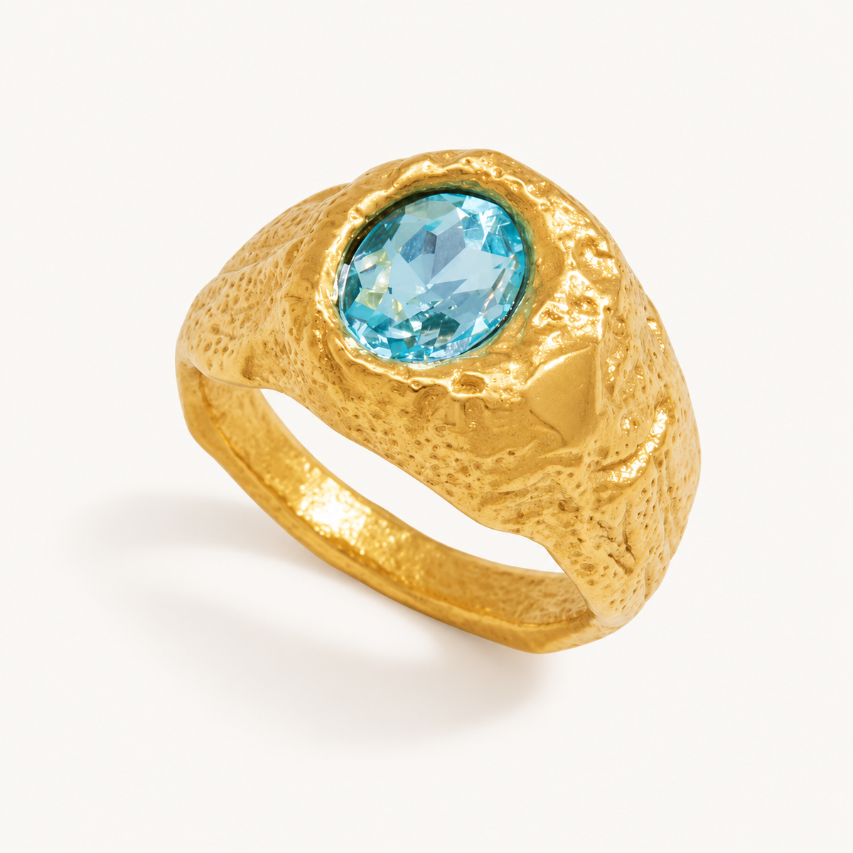 Luciana textured gold signet ring with an oval aqua zircon on warm ivory